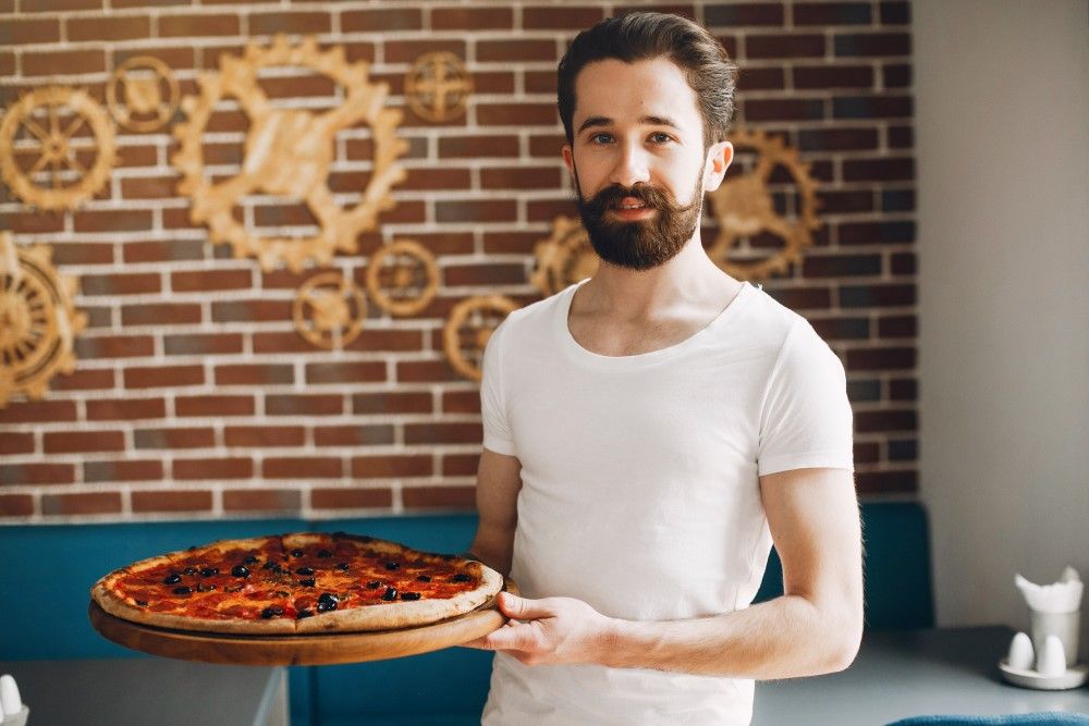Chef in the kitchen prepares pizza