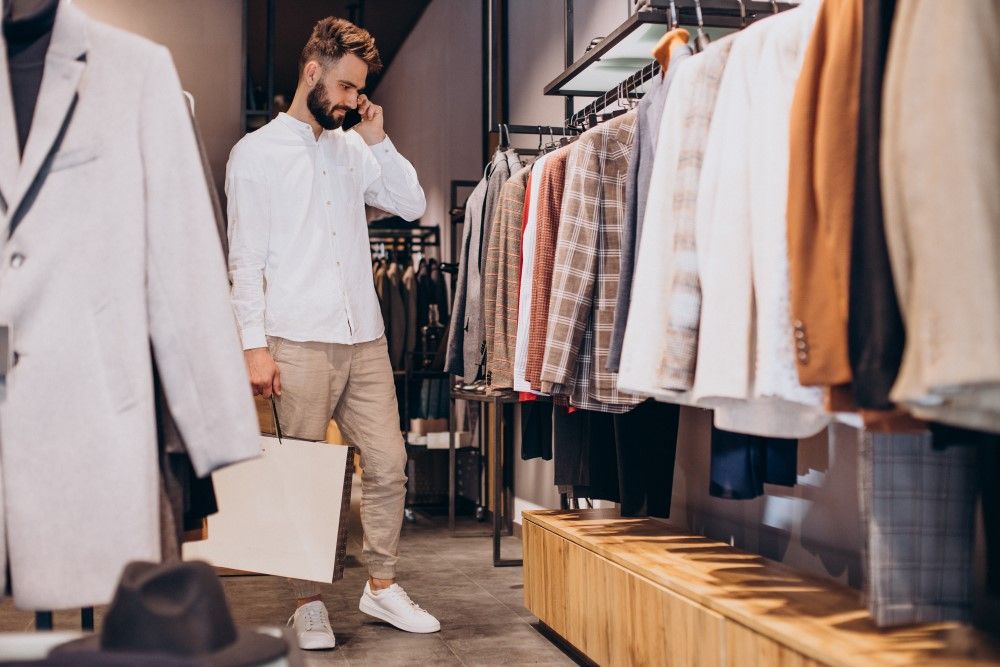 Young man shopping at menswear store and talking on the phone