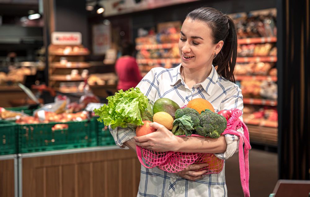 young-woman-in-a-supermarket-with-vegetables-and-fruits-buying-groceries